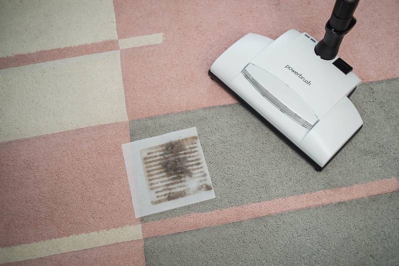 Sesalna glava na vzorčasti preprogi ob filtru z izvlečenim prahom in vlakni